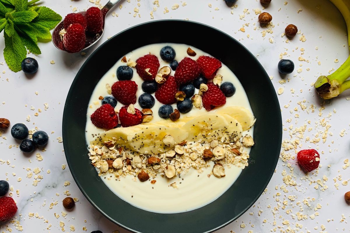 Tigela de iogurte com frutas vermelhas, banana, aveia e castanhas